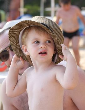 Baby girl with big hat posing on the beach