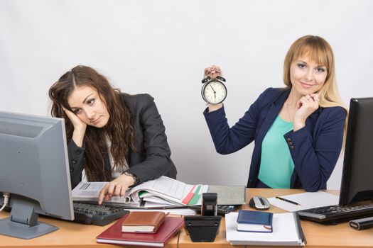 Two office workers wait for the end of the working day