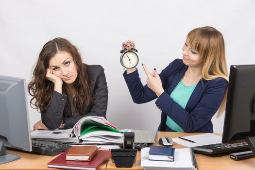  Office workers at the end of the day, one with a smile indicates a clock, another weary head props