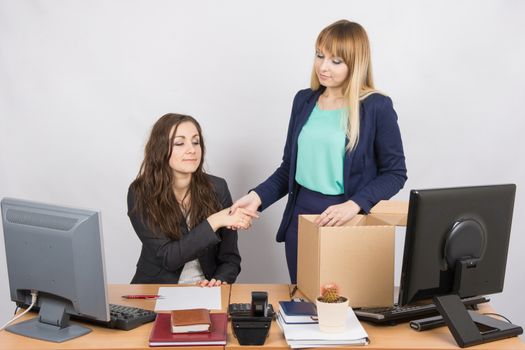 Girl in office standing with a smile in front of the box and shakes hands with a colleague