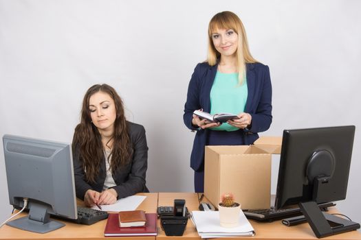 An employee in the office happily puts things out of the box next to a colleague