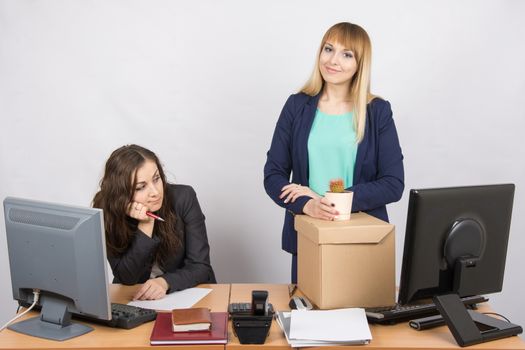 New employee in the office happily keeps things close sad colleague