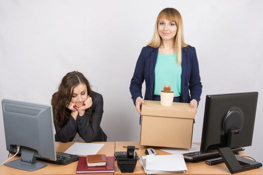 An employee in the office happily keeps things close sad colleague