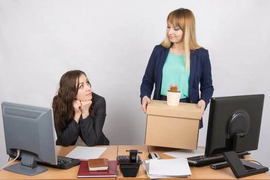 The girl in the office happily holding bags and looking at colleague