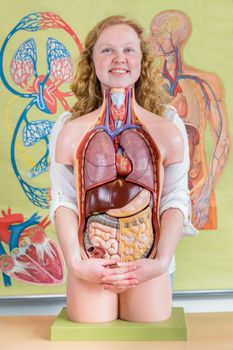 Female student embracing model of human torso with organs in biology lesson