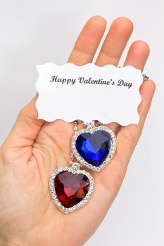 Hand showing red and blue jewelry hearts for valentine's day isolated on white background