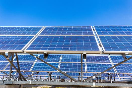 Metal frames with rows of blue solar panels and sky