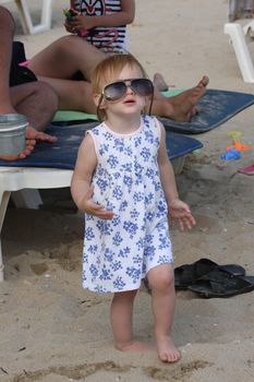 Baby girl with big glasses  posing on the beach