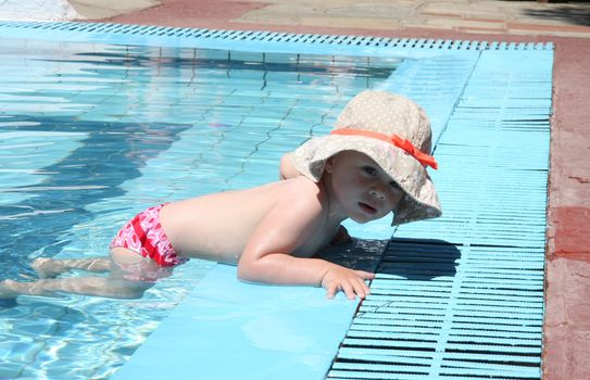 Baby girl trying to get out of swimming pool