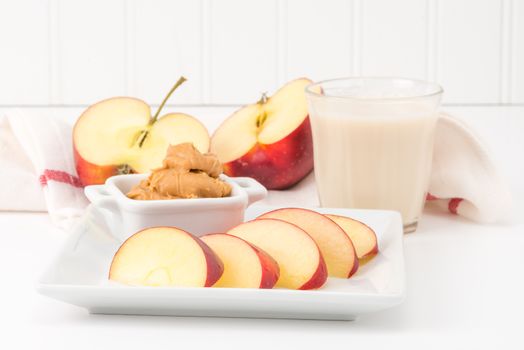 Health snack of fresh red apple and peanut butter with a glass of milk.