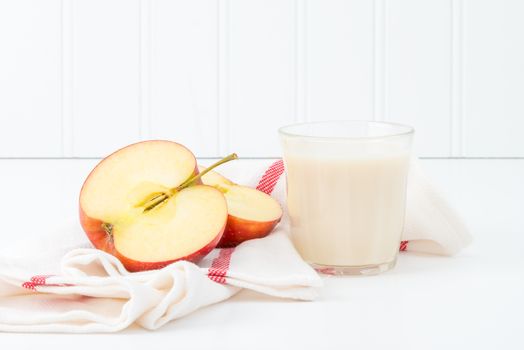 Snack of sliced fresh red apple and a glass of cold milk.