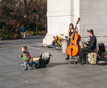 Manhattan, New York - December 06, 2015: Child left some money to street musicians playing during lazy Sunday afternoon in Washington Square Park.