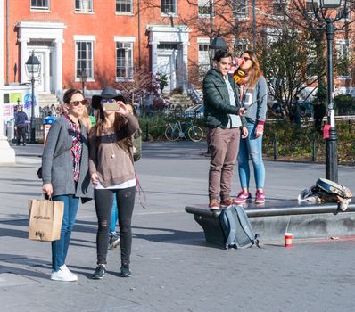 Manhattan, New York - December 06, 2015: People making selfies during lazy Sunday afternoon in Washington Square Park.