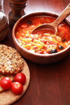 Nice wooden bowl with soup near bread and seasoning