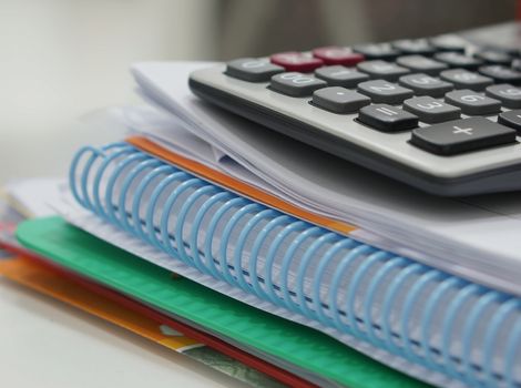 Paperwork, notebook and calculator placed on desk at office room.