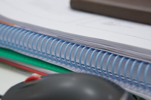 Stack of paperwork, notepad and computer mouse placed on table.