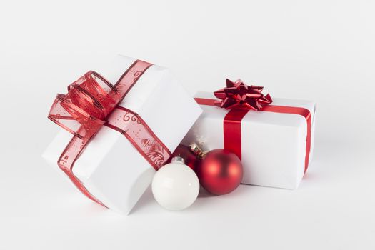 White Christmas presents with red ribbons and bow, red and white Christmas balls, isolated on white background