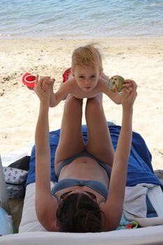 Mother and her baby girl playing on the beach