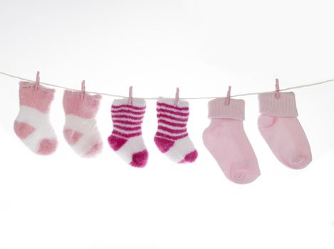 Pink and white baby socks on clothesline, isolated on white background