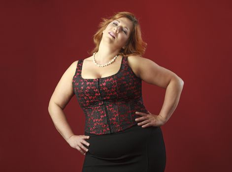 forty year old woman with red hair, wearing a red corset against a red background