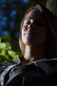 backlite portrait of a young woman sitting in a tree