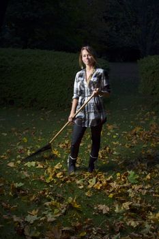woman in her twenties raking leaves at night