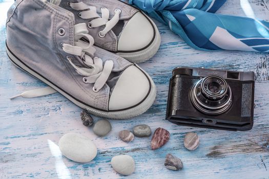 Travel still lifewith sneakers,camera and scarf on wooden board