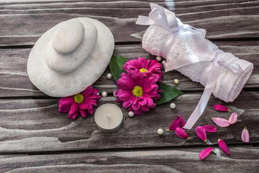 Spa concept. Rocks,candle,flowers and bath white towels on wooden background.