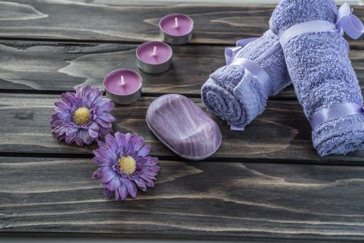 Spa concept. flowers,candles, soap and bath purple towels on wooden background