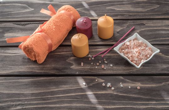 Spa concept. candles, aromatic salt, and bath orange towel  on wooden background
