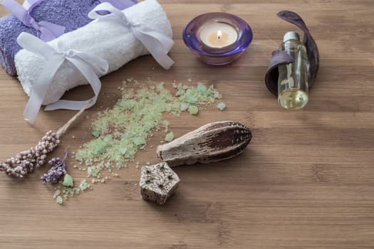 Spa concept. flowers,candles, aromatic salt,soap and bath purple and white towels on wooden background