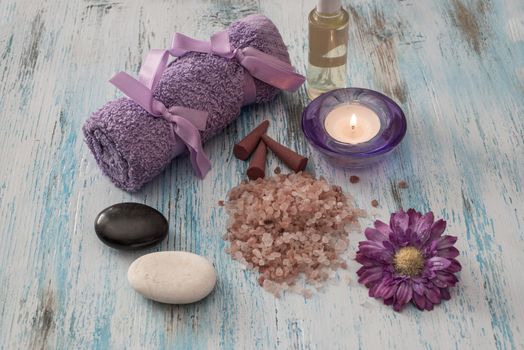 Spa concept. lavander oil flowers,candle, aromatic salt, and bath purple towels on wooden background