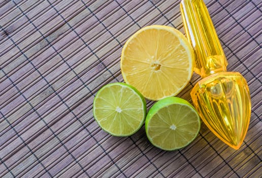 Lemon, limes and plastic juicer with handle on a wooden background
