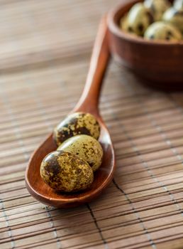 Quail eggs into wooden spoon and bowl blury backround