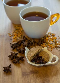 Tea, dried cinnamon, vegan cookies , and anise on wooden background