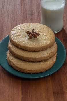 Glass of fresh milk and danish cookies on a textural wooden surface.