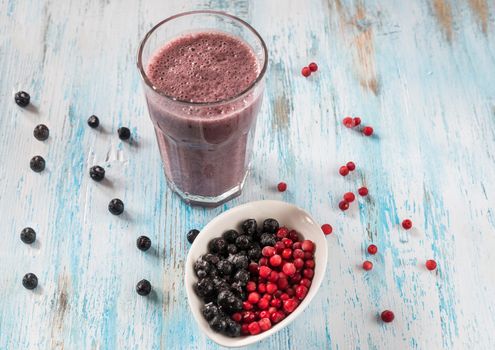 Berry smoothie with almond milk, cranberries,aronia and black currants in a glass on a dark background, top view