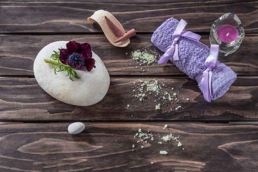 Spa concept. flowers,candles, aromatic salt and bath purple towel on wooden background