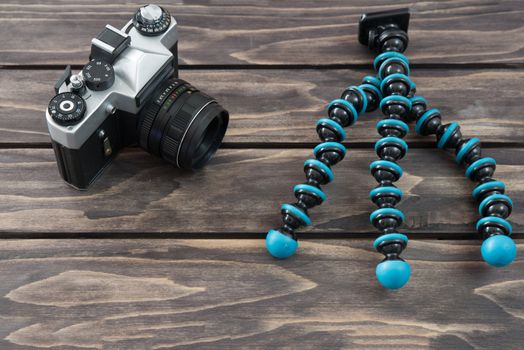 
Close up view of a flexible type tripod and vintage camera on wooden background
