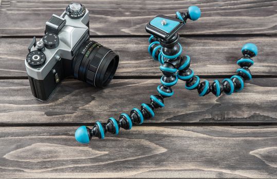 Close up view of a flexible type tripod and vintage camera on wooden background