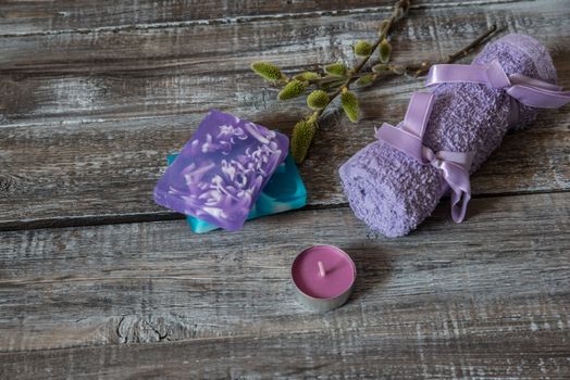 Spa concept. flowers,candles,soap and bath purple towels on wooden background