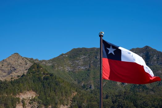 Flag of Chile fluttering in the wind on a ship anchored in Cumberland Bay on Robinson Crusoe Island, one of three main islands making up the Juan Fernandez Islands some 400 miles off the coast of Chile.