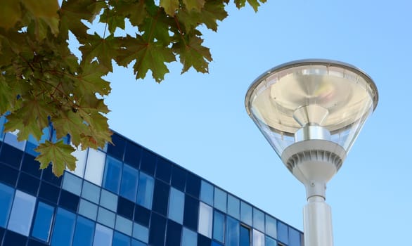 modern street lamp on background of blue sky, modern buildings, and maple leaves