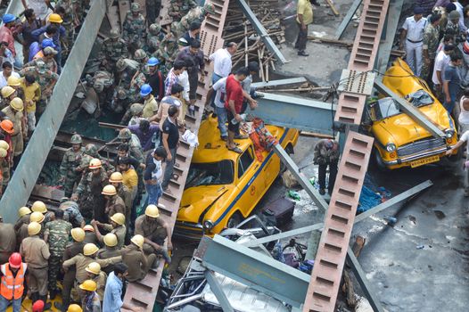 INDIA, Kolkata: Indian soldiers, rescue workers and volunteers try to free people trapped under the wreckage of a collapsed flyover bridge in Kolkata on March 31, 2016. At least 14 people were killed and dozens more injured when a flyover collapsed in a busy Indian city on March 31, an official said, as emergency workers battled to rescue people trapped under the rubble.