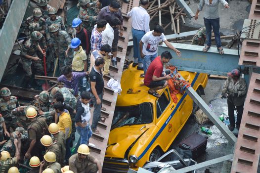 INDIA, Kolkata: Indian soldiers, rescue workers and volunteers try to free people trapped under the wreckage of a collapsed flyover bridge in Kolkata on March 31, 2016. At least 14 people were killed and dozens more injured when a flyover collapsed in a busy Indian city on March 31, an official said, as emergency workers battled to rescue people trapped under the rubble.