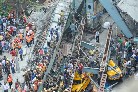 INDIA, Kolkata: Indian soldiers, rescue workers and volunteers try to free people trapped under the wreckage of a collapsed flyover bridge in Kolkata on March 31, 2016. At least 14 people were killed and dozens more injured when a flyover collapsed in a busy Indian city on March 31, an official said, as emergency workers battled to rescue people trapped under the rubble.