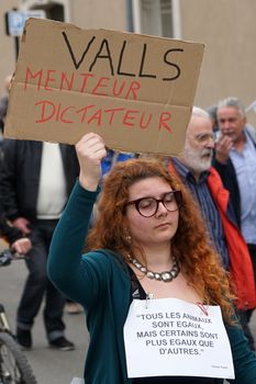 FRANCE, Nîmes: A protester holds a sign reading 'Valls, liar, dictator' as thousands of protesters march during a demonstration against the French government's planned labour law reforms on March 31, 2016 in Nîmes. France faced fresh protests over labour reforms just a day after the beleaguered government of President Francois Hollande was forced into an embarrassing U-turn over constitutional changes.