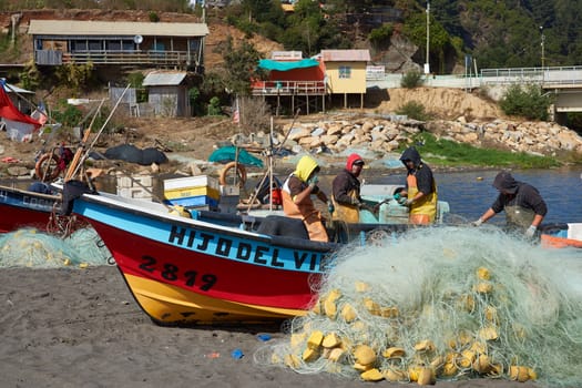 Colourful fishing boats and fishing nets on the beach in the small fishing village of Curanipe in the Maule Region of Chile.