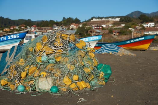 Colourful fishing boats and fishing nets on the beach in the small fishing village of Curanipe in the Maule Region of Chile.