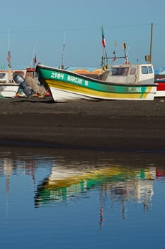 Colourful fishing boats reflected in a river in the small fishing town of Curanipe, Chile.